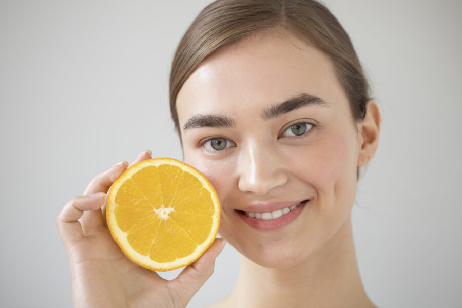 portrait beautiful woman with clear skin holding sliced orange fruit